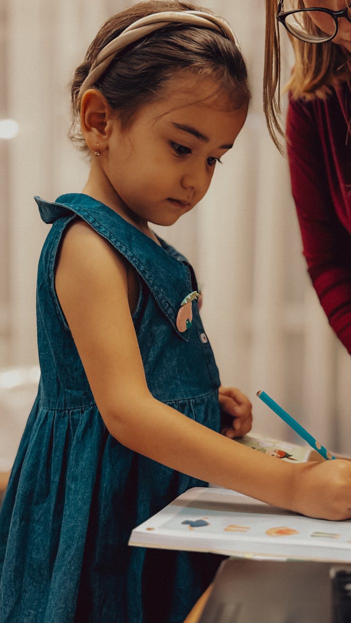 Crafting Captivating Headlines: Your awesome post title goes here A young girl in a blue dress drawing with a pencil, focused on her artwork.