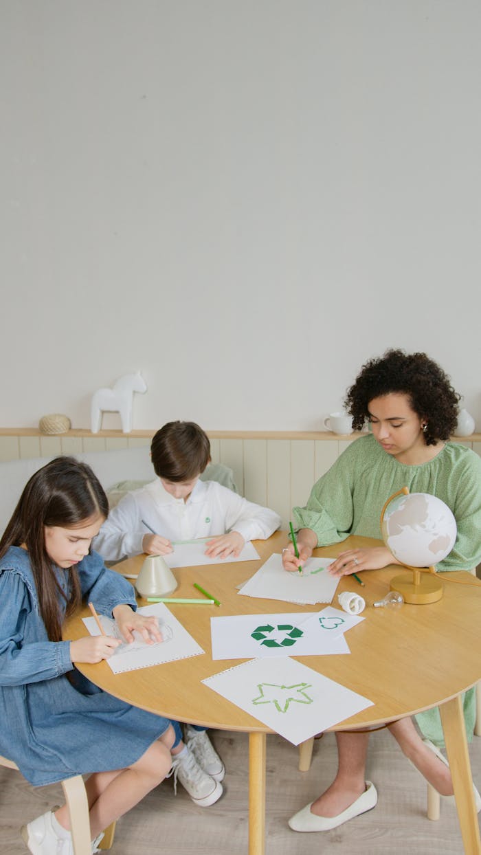 Children engaged in a classroom activity about recycling with their teacher, using arts and crafts.
